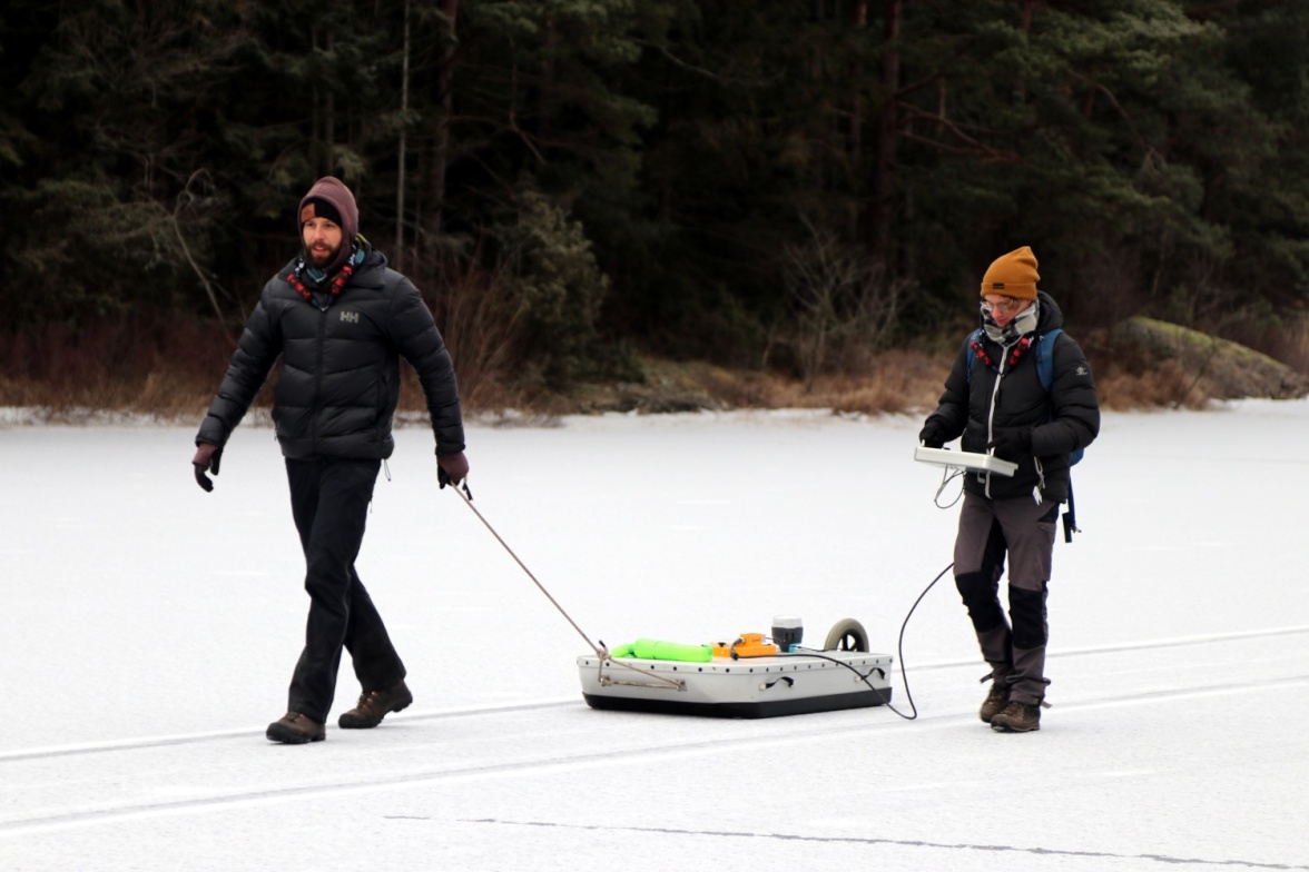 Two master students, Fredrik Andersson and Tobias Möhl, participated in the sampling. Here they are pulling the geo- radar (Malå Geoscience Ramac) equipment over the ice. Photo: Leif Klemedtsson.